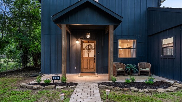 A dark blue house with a wooden front door, two wicker chairs, and a number '200' sign in front. - Wine Trail Retreat w/ Fire Pit, Cold Plunge, Grill, Walk to Downtown JC! (Johnson City)