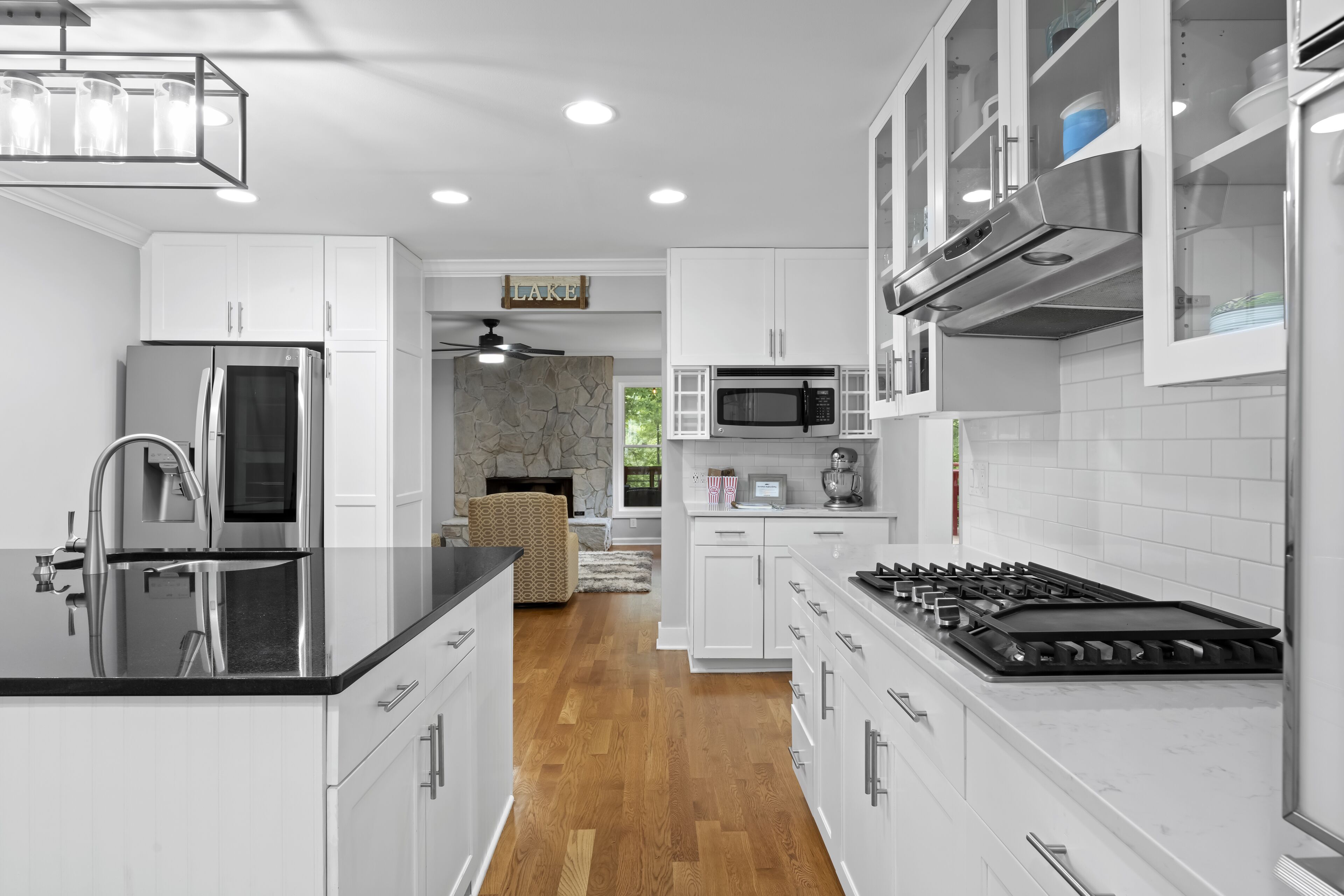 A modern kitchen with white cabinetry, stainless steel appliances, and a wooden floor.
