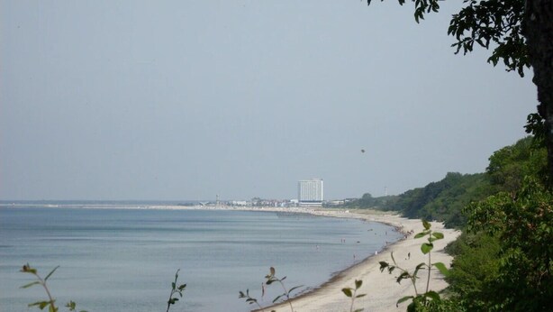 Une plage côtière offrant une vue dégagée sur la mer et sur un bâtiment situé au loin.