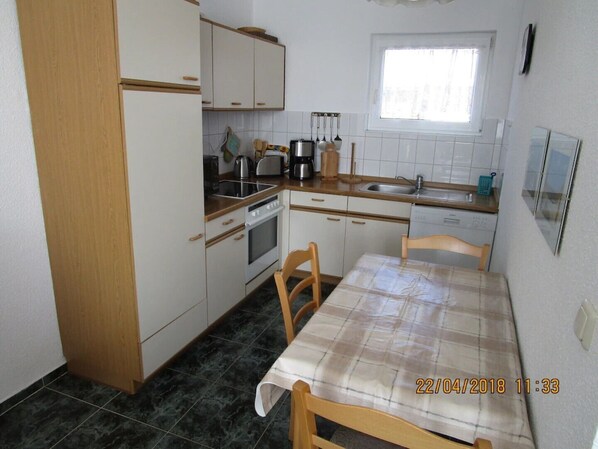 A compact kitchen with white cabinets, a wooden countertop, a built-in oven, a sink, and a window above the sink. - Apartment (A) with 45sqm in the vacation home "Seebriese". (Rostock)