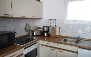 A kitchen with white cabinets, a microwave, a stove, a sink, and various kitchen utensils. - Apartment (A) with 45sqm in the vacation home "Seebriese". (Rostock)