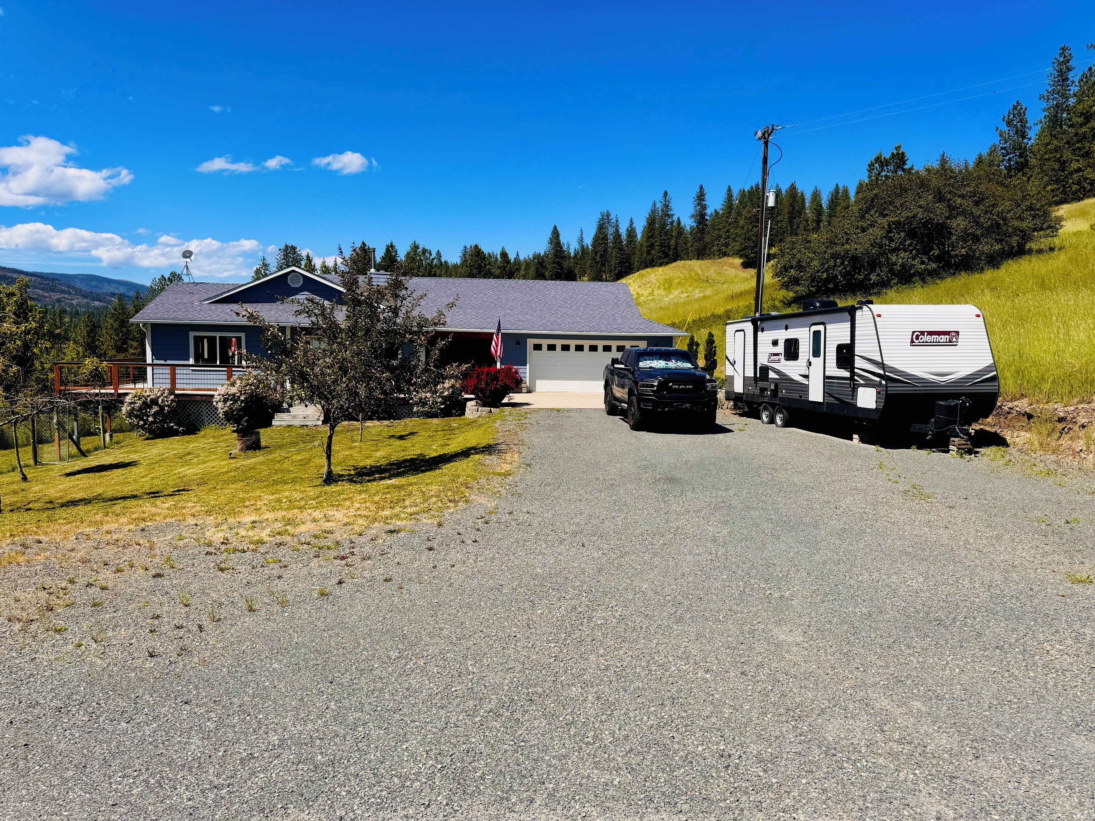 A house with a gravel driveway, a parked truck, and a trailer.