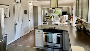A modern kitchen with white cabinetry, a central island, and a stainless steel oven.