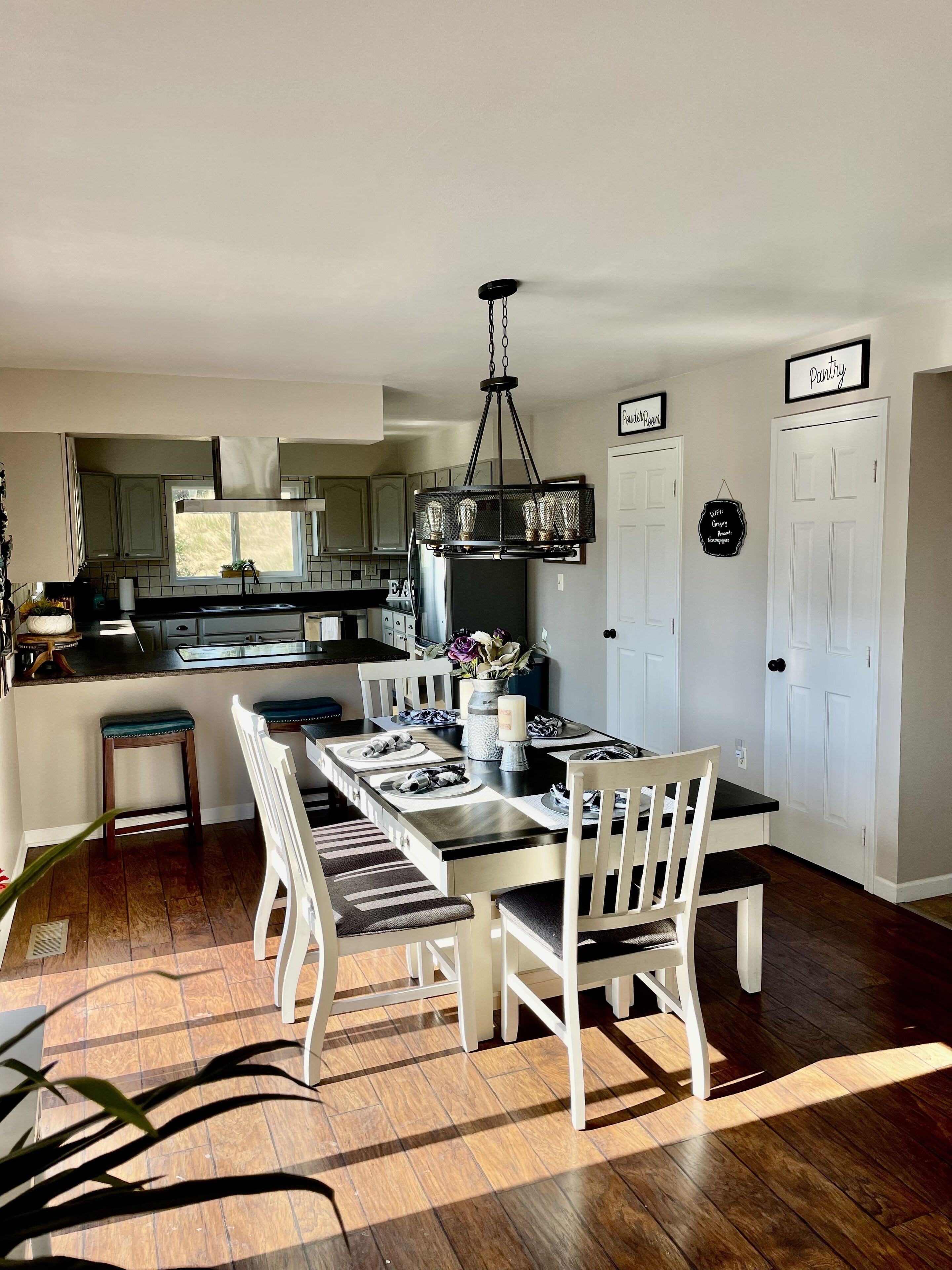 Cocina moderna con comedor, que incluye una isla central, iluminación colgante y vistas al exterior.