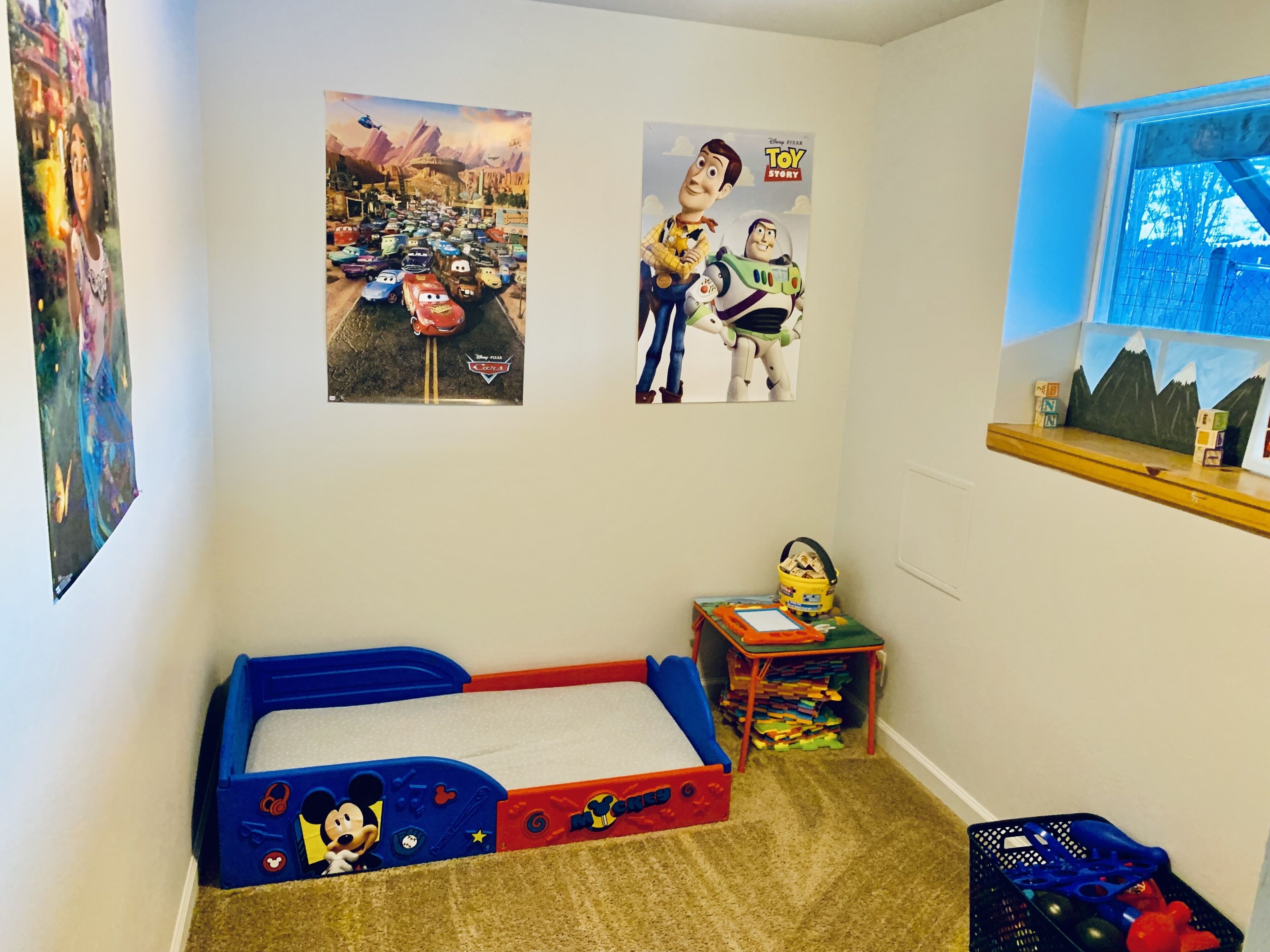 Une chambre d’enfant avec un lit, des affiches et des jouets.