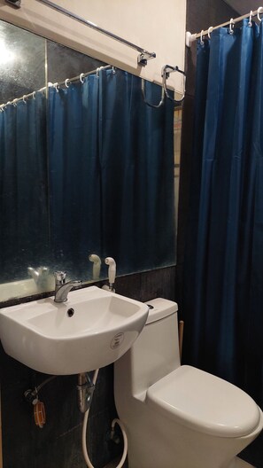 A bathroom with a white sink, a toilet, and blue curtains. - 2bed Transient House Villa in Davao City Free Wifi (Davao)