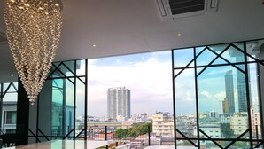 A modern interior with large windows offering a city view, a chandelier, and a glass table. - S3 Siam Bangkok (Bangkok)