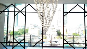 A modern interior with a large marble table, a decorative chandelier, and large windows offering a city view. - S3 Siam Bangkok (Bangkok)