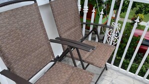 Two wicker chairs with dark metal frames on a balcony with white railings and a stone floor. - Lovely 2-bedroom Apt, Sleeps 3, Warm & Cosy (Potters Village)