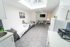 A compact kitchen with a bed, a dining area, and a TV. - Large Studio 10 Minute Train Journey to the City! (Birmingham)