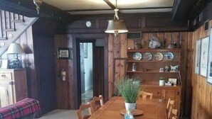 A wooden dining table with chairs, a potted plant, and a staircase leading to another room.