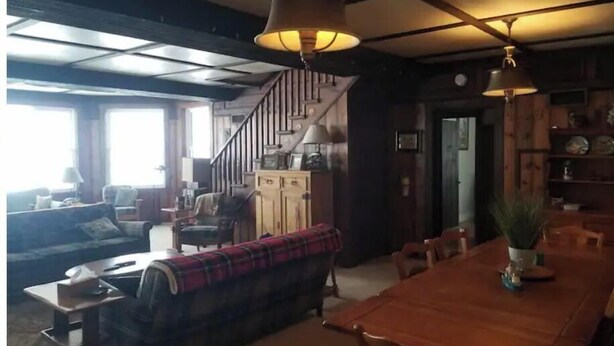 A cozy living room with a sofa, a dining table, and a staircase.