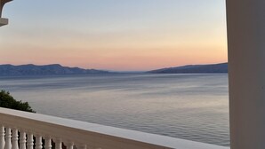 Uma varanda com vista para um corpo de água calmo e montanhas ao longe.