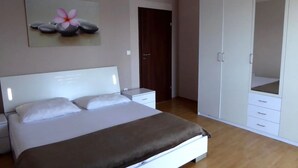 Quarto com cama, mesa de cabeceira, guarda-roupa e porta.