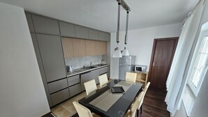 Uma cozinha moderna com armários cinza, uma mesa de jantar com cadeiras, uma geladeira e um micro-ondas.