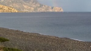 A coastal scene with a rocky shoreline, a mountain in the background, and a rainbow in the sky. - Stunning 2-bedrooms Private Cottage in Palaiochora (Kantanos-Selino)