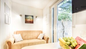 Une pièce avec un canapé beige, un tableau encadré au mur et un panier de fruits sur la table.