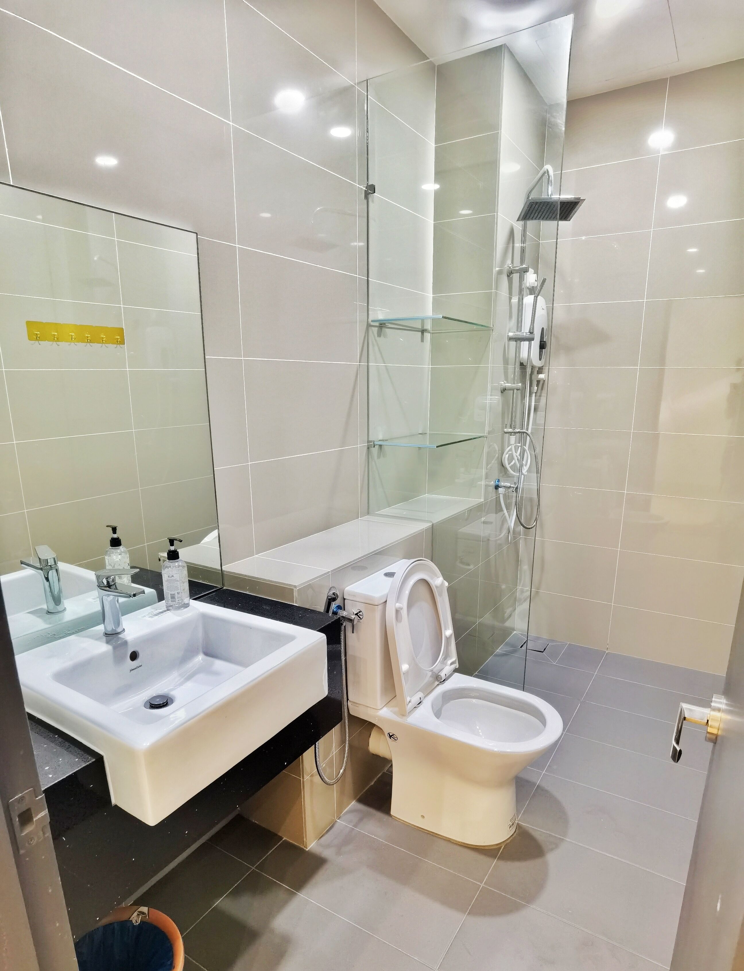A modern bathroom with a glass shower enclosure, a white sink with a mirror, and a toilet.