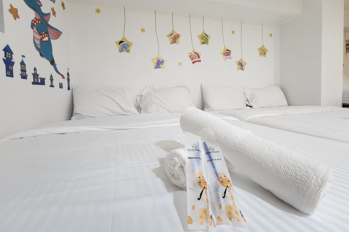 A hotel room with two beds, white bedding, and a wall decorated with star-shaped stickers and a cartoon character.