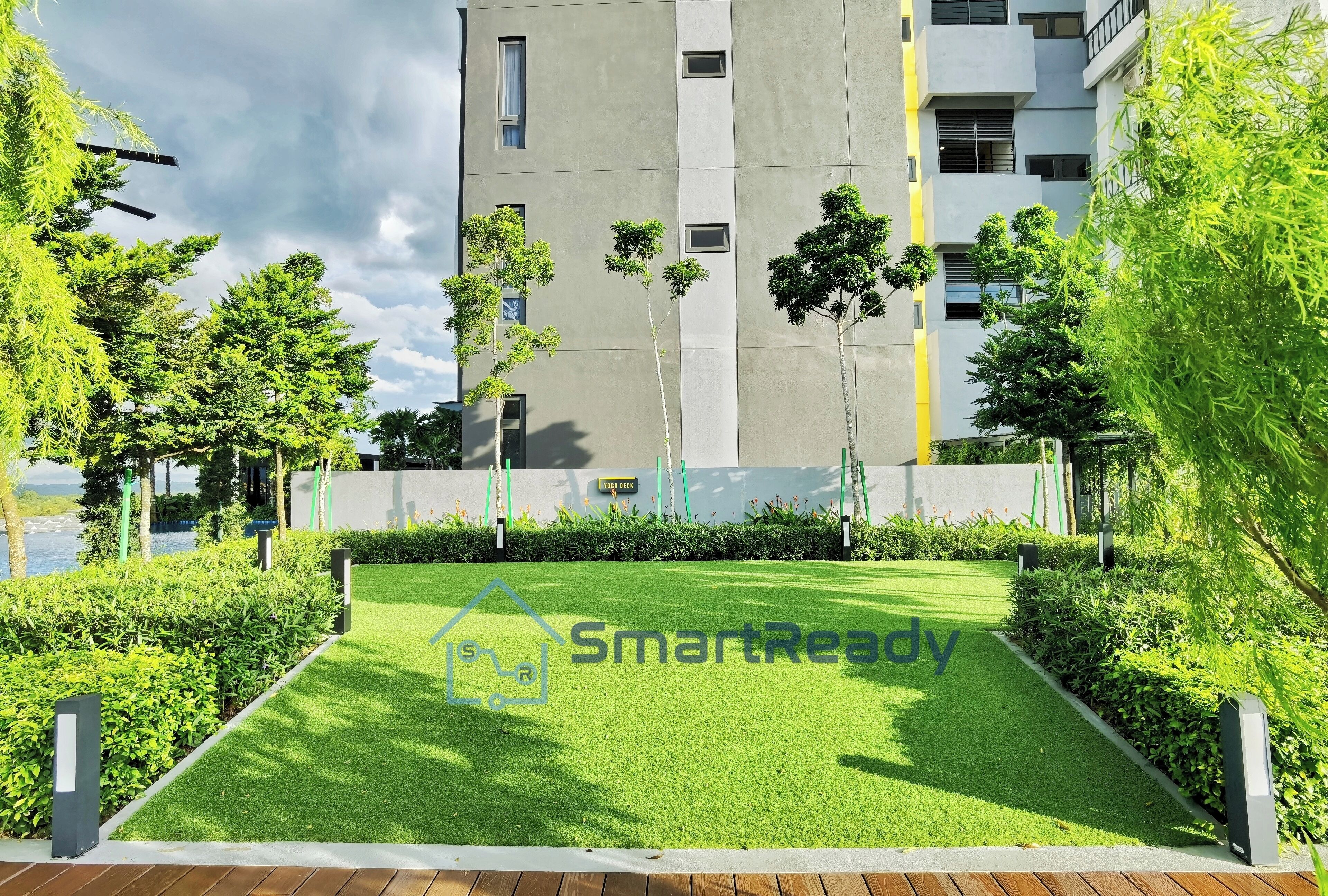 A modern building with a flat roof, a well-maintained lawn, and a variety of trees and shrubs.