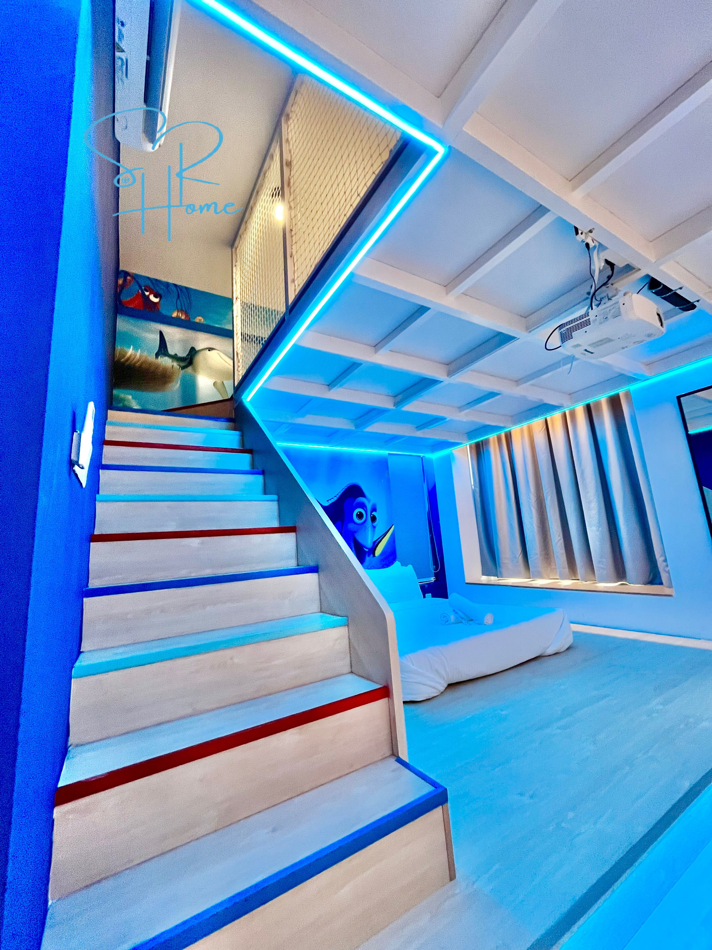 Un escalier moderne doté d’un éclairage à DEL bleuté, d’un projecteur et d’une fresque représentant un pingouin.