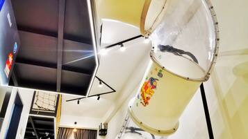 A room with a basketball hoop, a large white drum, and a wall with children's book illustrations.