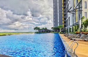 A swimming pool with a view of a modern building and a cloudy sky.