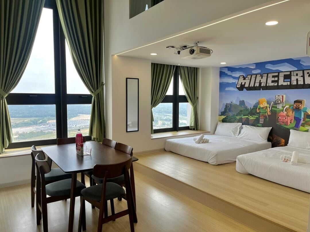 Ein Hotelzimmer mit Esstisch, zwei Betten, einem Projektor und einer Wandmalerei zum Thema Minecraft.