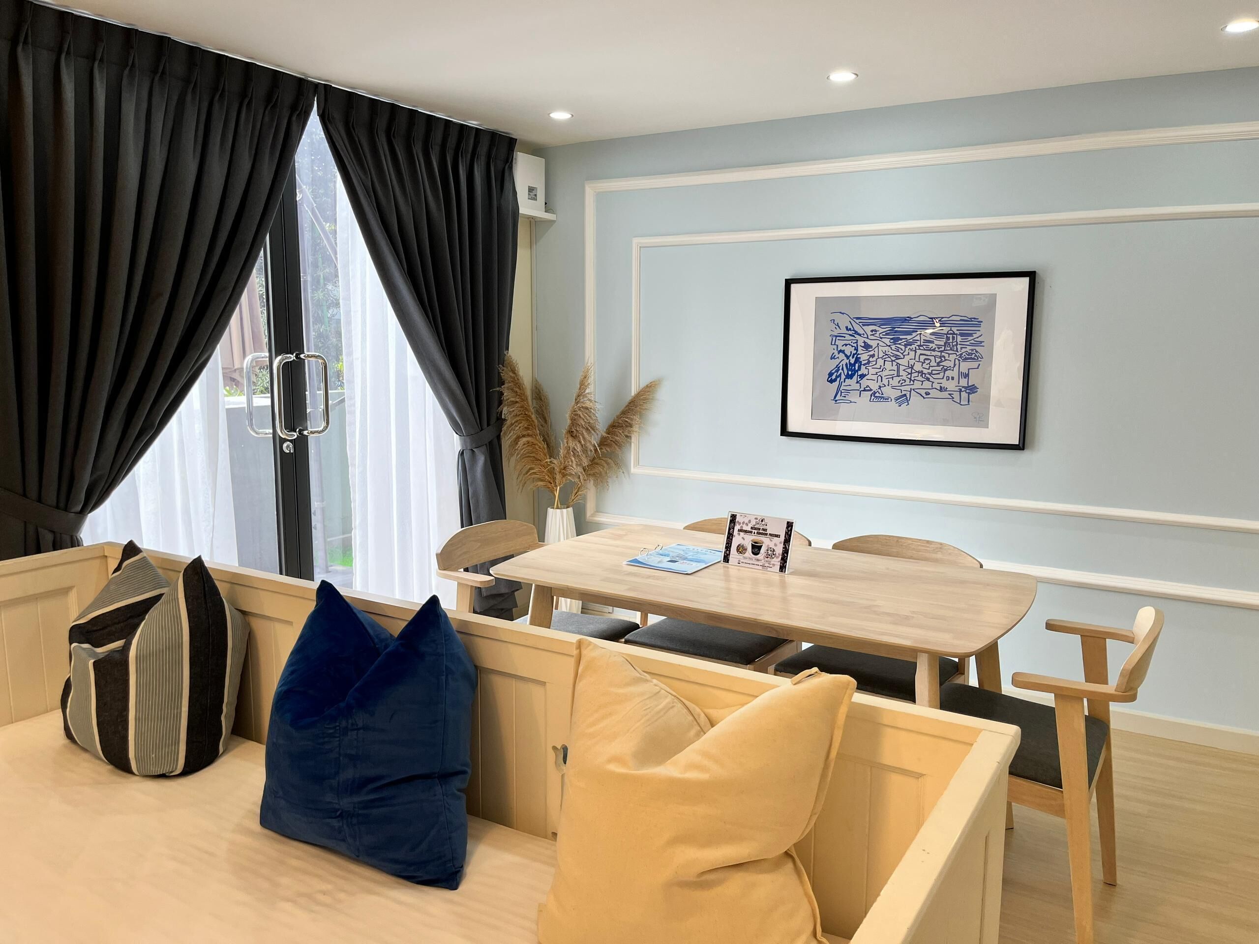 A modern room with a dining area, a sofa, and a window with curtains.