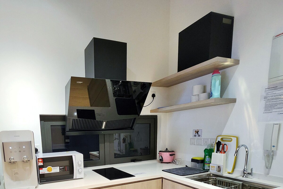 A compact kitchen with a built-in microwave, coffee maker, and a small sink.