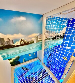 A room with a mural of a cityscape and a large window with a blue mosaic pattern.
