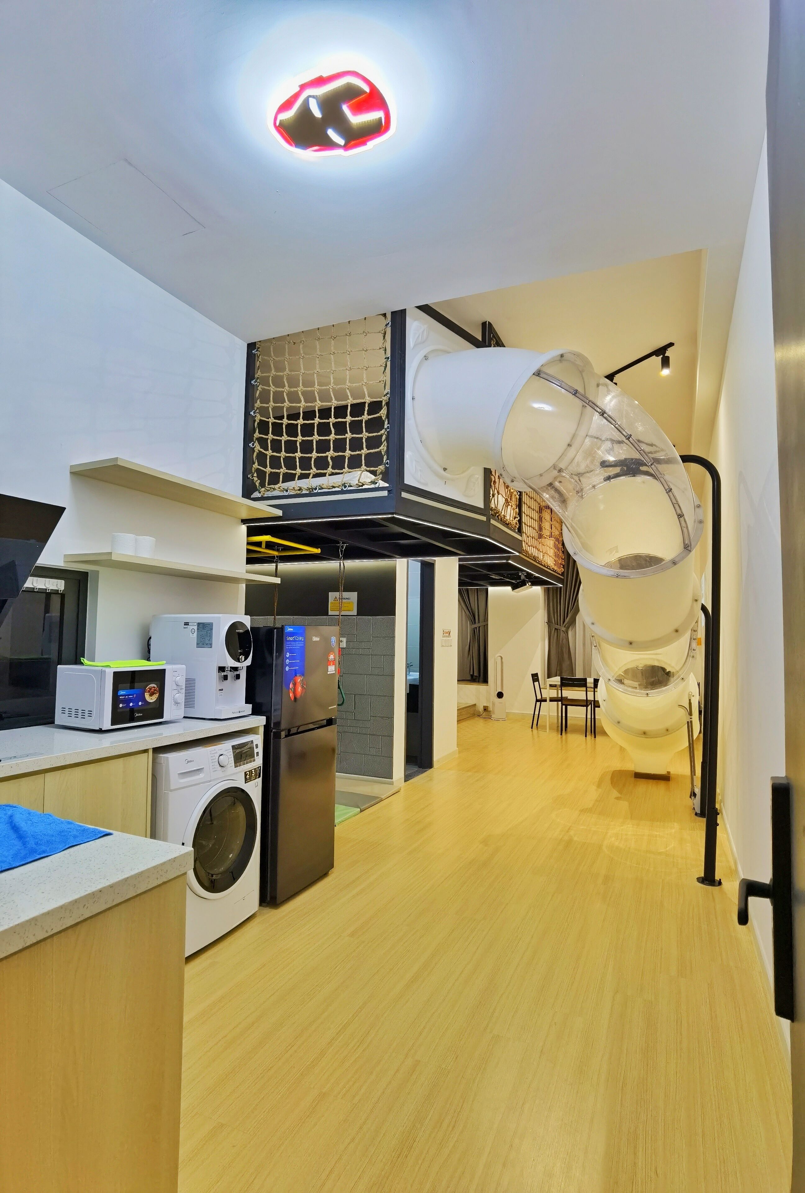 A modern kitchen with a built-in washing machine, a microwave, and a refrigerator.