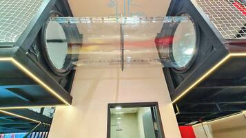 A modern interior with a glass ceiling, a visible elevator, and a sign with a heart symbol.