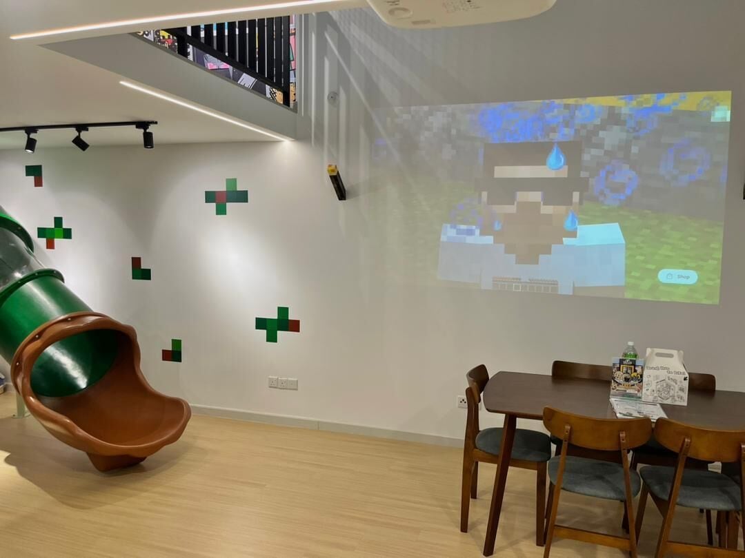 A modern room with a slide, a projection screen, and a dining area.