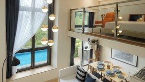 A modern hotel room with a sofa, dining table, and a balcony with a view.