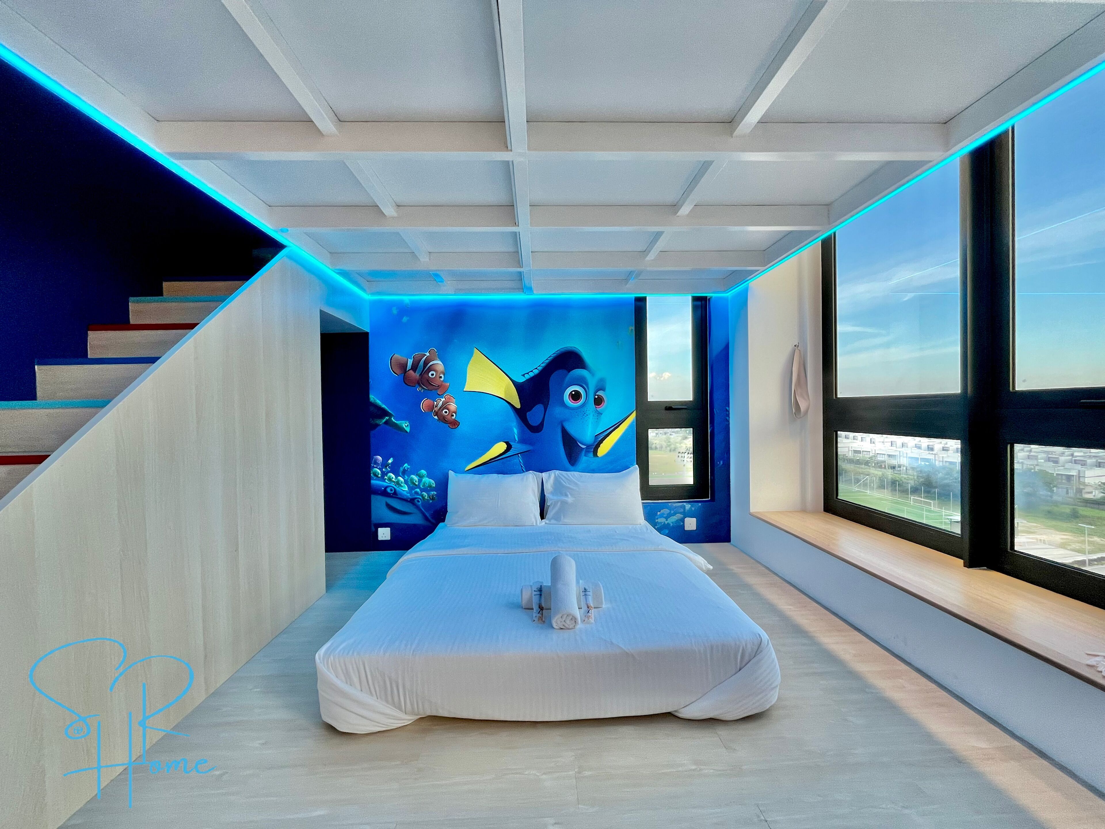 A modern bedroom with a large bed, a mural of a blue fish, and a city view through the window.
