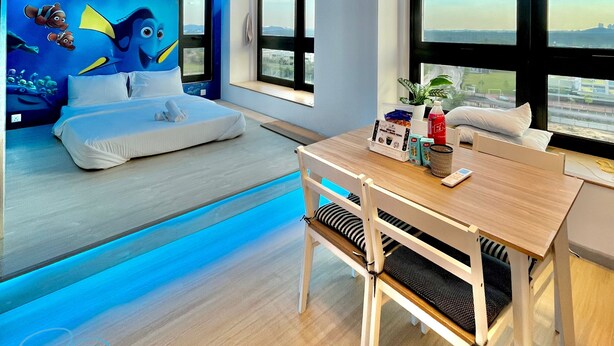 A modern room with a bed, a dining table, and a large window.