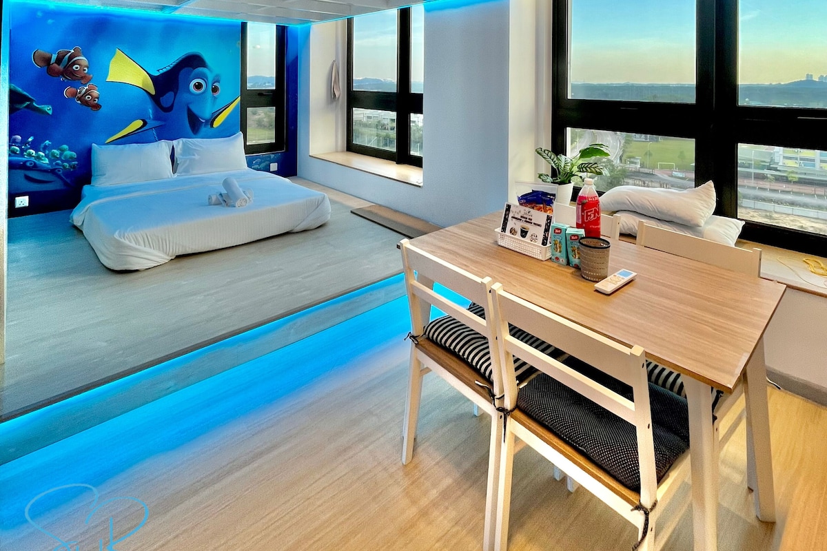 A modern room with a bed, a dining table, and a large window.