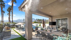 Eine Außenpatio mit Essbereich, Grill und Pool.