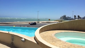 A swimming pool with a view of the beach and city skyline.