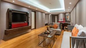 A modern living room with a flat-screen TV, a coffee table, and seating area. - Suning Universal Hotel All-Suites (Nanjing)