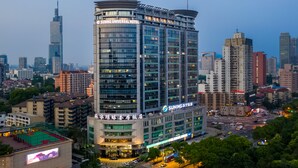 A high-rise hotel with multiple floors, a prominent sign for the Suning Universal Hotel, and a view of the surrounding cityscape. - Suning Universal Hotel All-Suites (Nanjing)