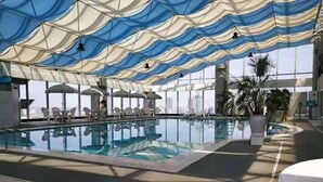 An indoor swimming pool with a covered area, clear glass walls, and a tiled floor. - Suning Universal Hotel All-Suites (Nanjing)