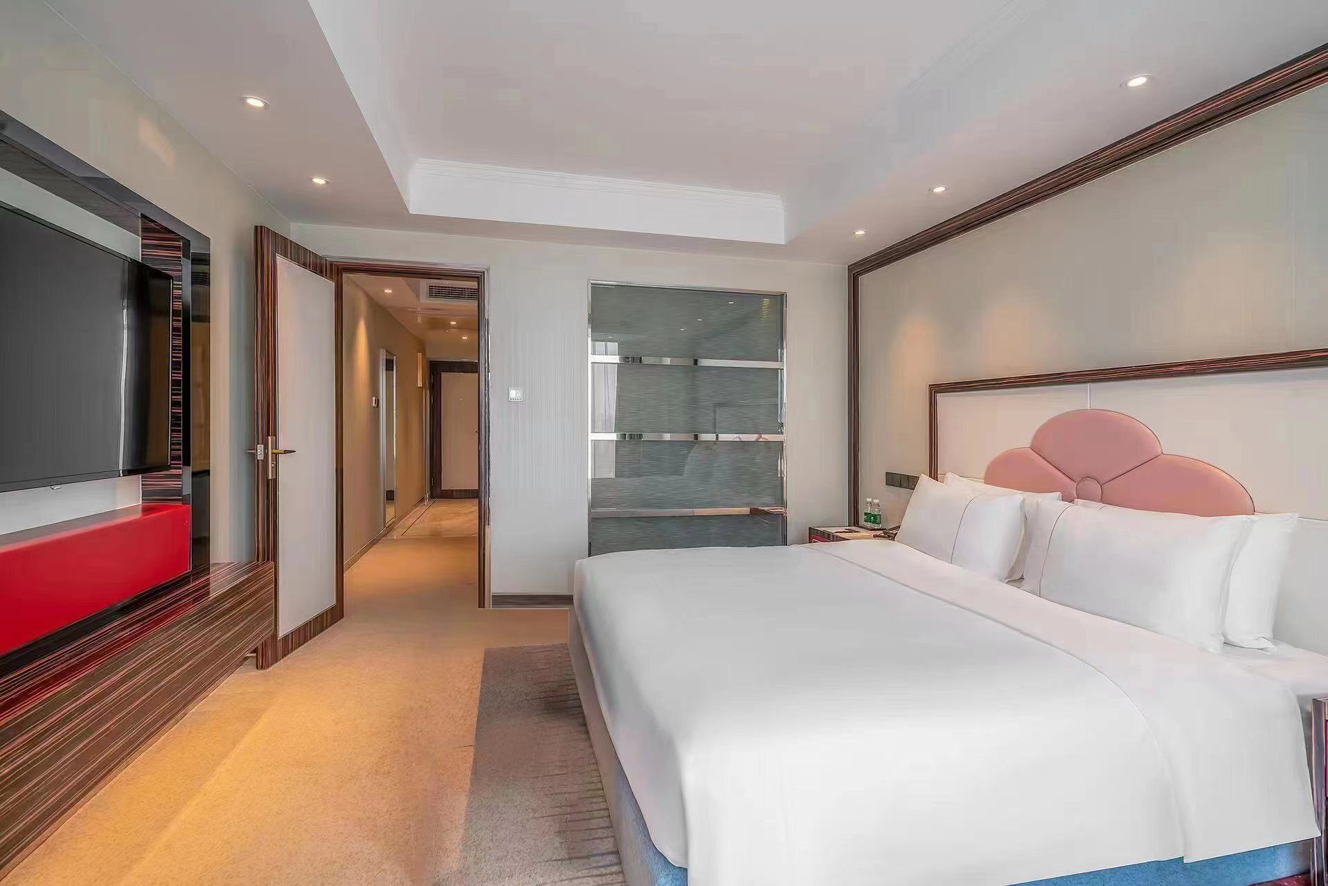 A hotel room with a large bed, a TV, and a wardrobe.