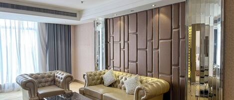 A spacious living room with a beige sofa, two armchairs, and a marble coffee table.