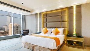 A hotel room with a large bed, a chair, a nightstand, and a view of the city. - Suning Universal Hotel All-Suites (Nanjing)