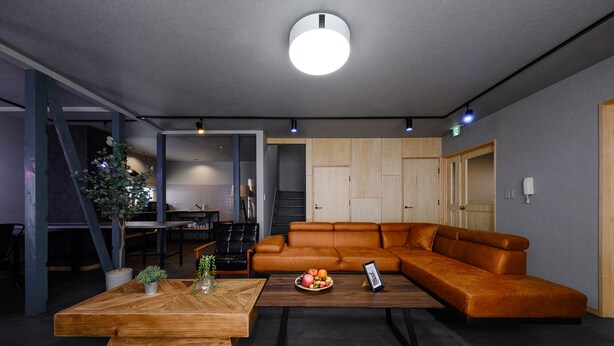 Una sala de estar moderna con un sofá modular, una mesa de centro de madera y un comedor al fondo.