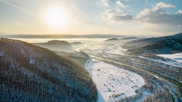 Un paisaje invernal con campos nevados, un río y montañas distantes bajo un cielo despejado.