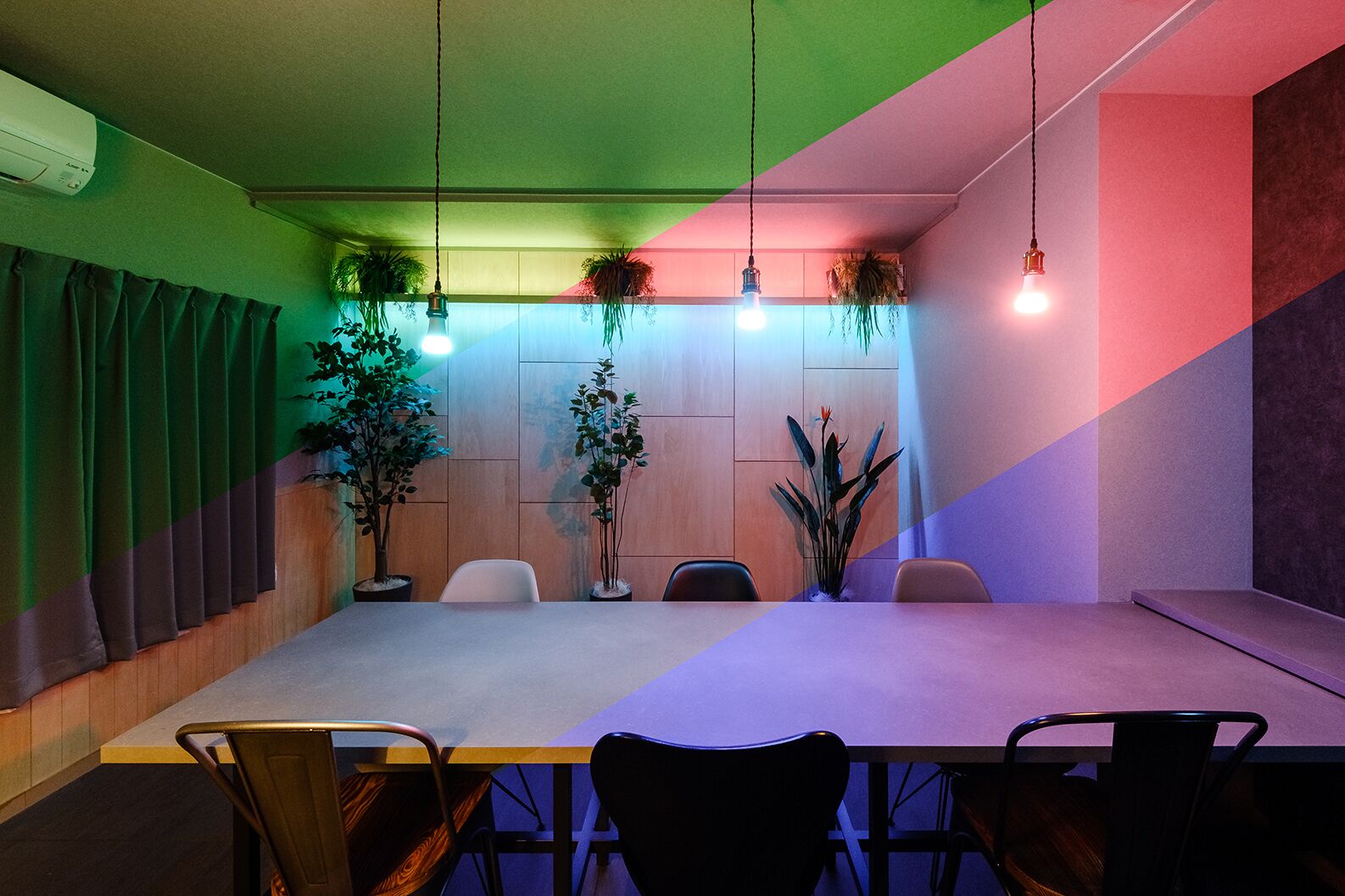 A conference room with a long table, several chairs, and hanging plants.