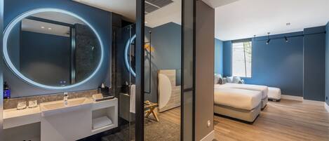 Un baño moderno con un espejo grande, lavamanos dobles y una cabina de ducha de vidrio.